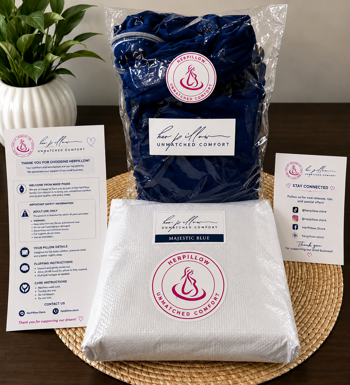 Herpillow packaging with blue and white pillows on a wooden surface with plant and cards.